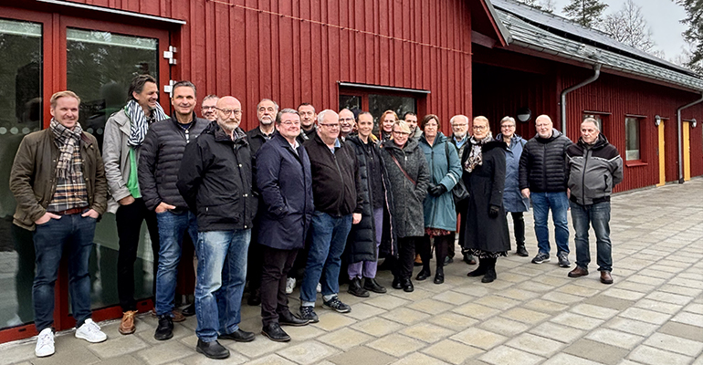 En grupp människor framför en röd fasad.