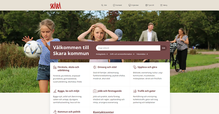Skärmklipp på Skara kommuns nya webbplats. En toppmeny med flera rubrikboxar i mitten. Bakom boxarna är det ett foto på två barn i förgrunden och några vuxna i bakgrunden.