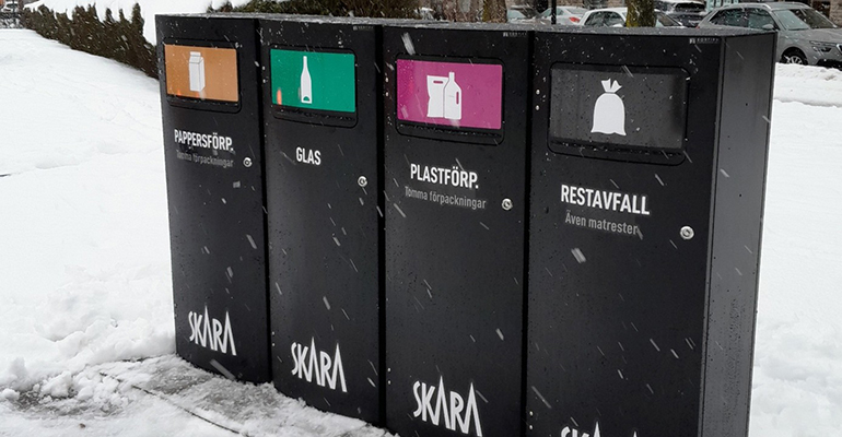 Fyra stycken sopsorteringskärl står bredvid varann. På kärlen står texten pappersförp, glas, plastförp och restavfall.