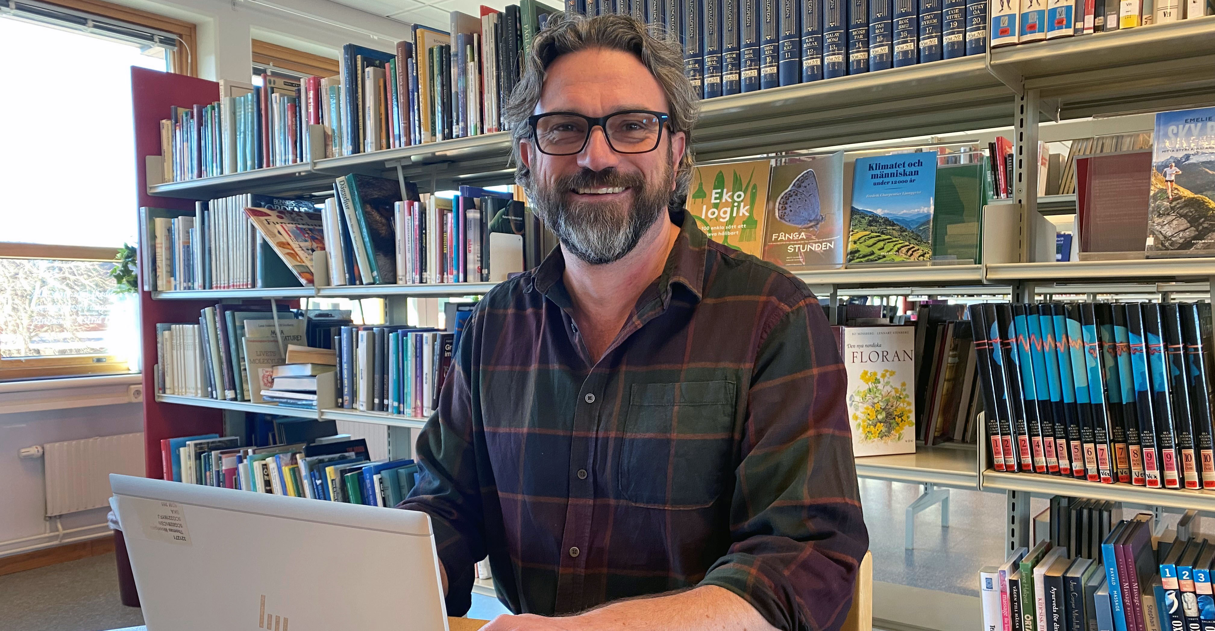 Thomas Woodgate är en av lärarna på IB-programmet på Katedralskolan som är med och utvecklar programmet. Han sitter vid en dator och arbetar. i bakgrunden i är det bokhyllor med fyllda med böcker.