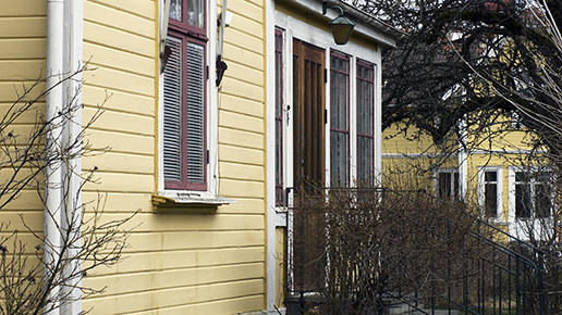 Detalj av entré på ett gult hus med träfasad.