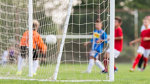 Genrebild fotbollsspelare sedda genom nätet på ett mål