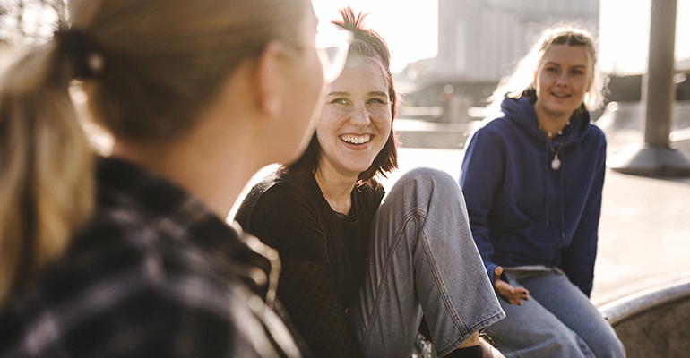 Tre glada tjejer tittar på varann. 
