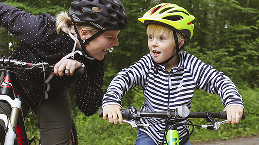 En mamma och en son står vid sina cyklar på en liten väg ute i naturen